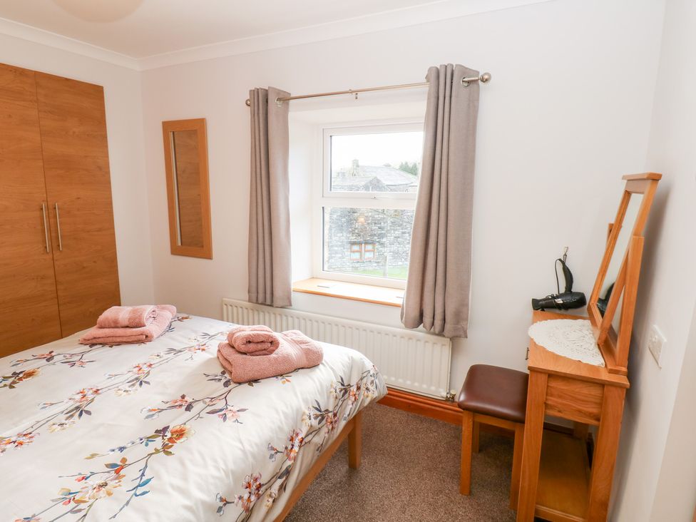 A bedroom with a bed and dressing table at Stoneleigh Cottage in Muker