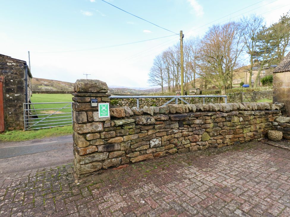 An outdoor area with a stone wall and gate at Stoneleigh Cottage in Muker