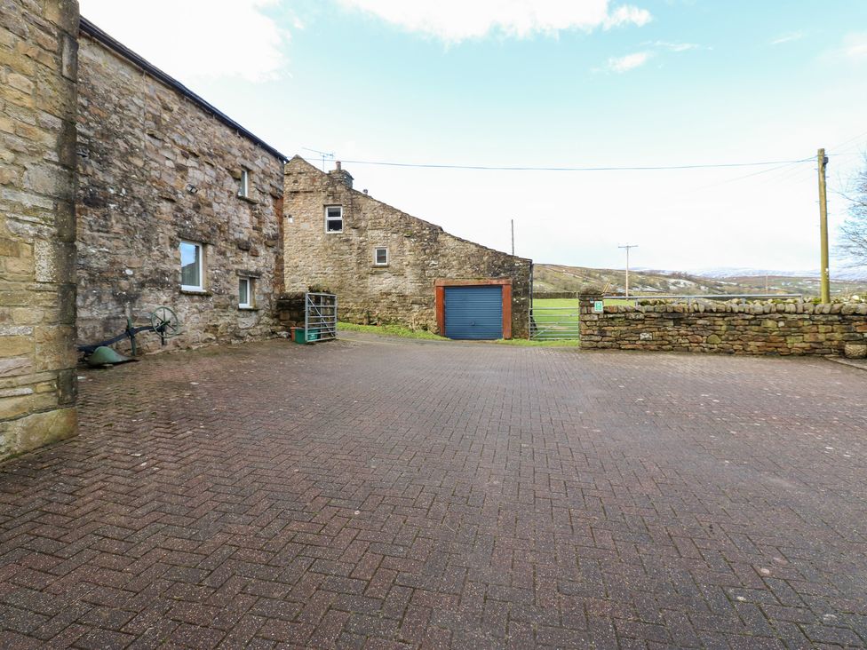 An outdoor area with stone walls and a garage at Stoneleigh Cottage Muker