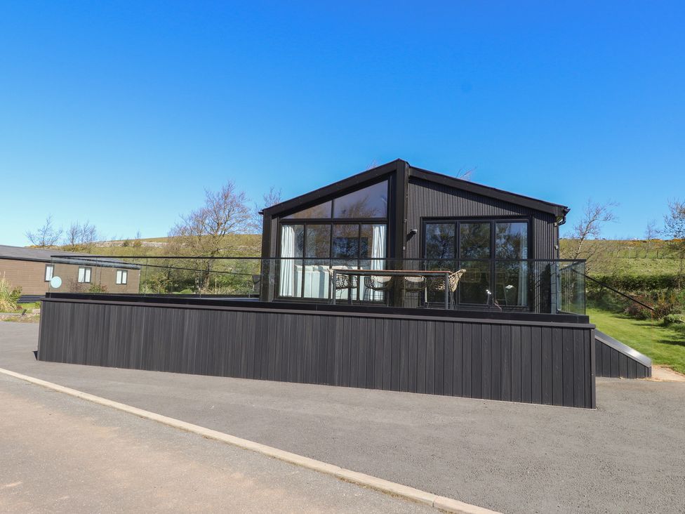 A house with a deck and glass railing at Encil Gyfrinfa in Gwynus, near Llithfaen