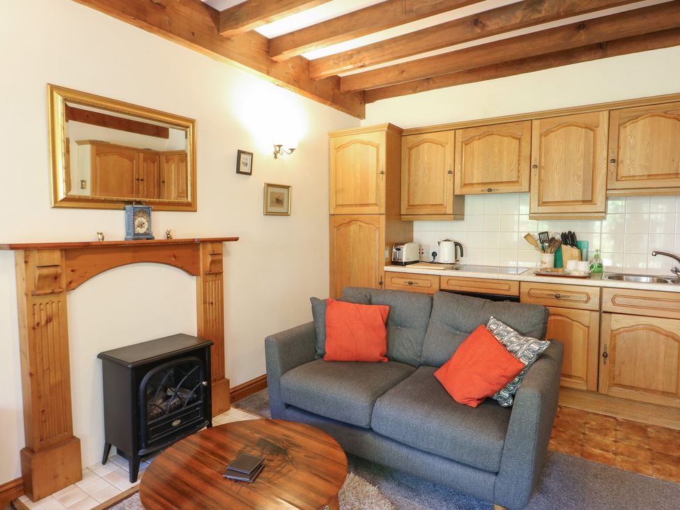 A living room with a sofa and kitchen area at Royal Oak Farm Cottage in Betws-y-Coed