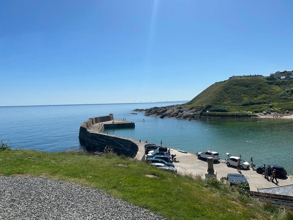 A view of a harbor with a pier and parked cars at The Breakers in Newburgh, Aberdeenshire