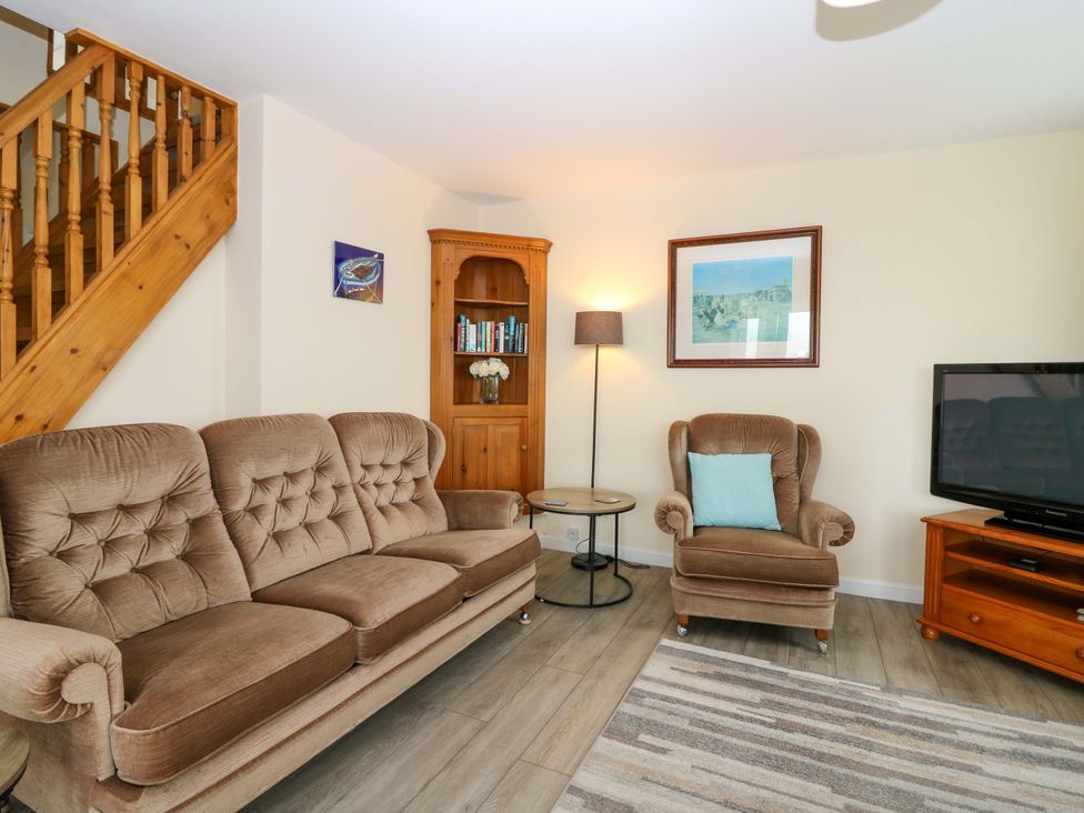 A living room with a sofa, armchair, and bookshelf at The Breakers in Newburgh, Aberdeenshire