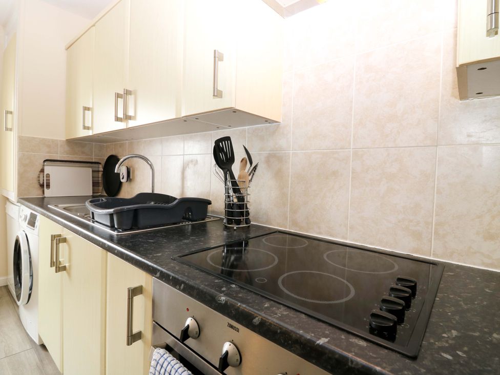 A kitchen with cabinets, stove, sink, and washing machine at The Breakers in Newburgh, Aberdeenshire