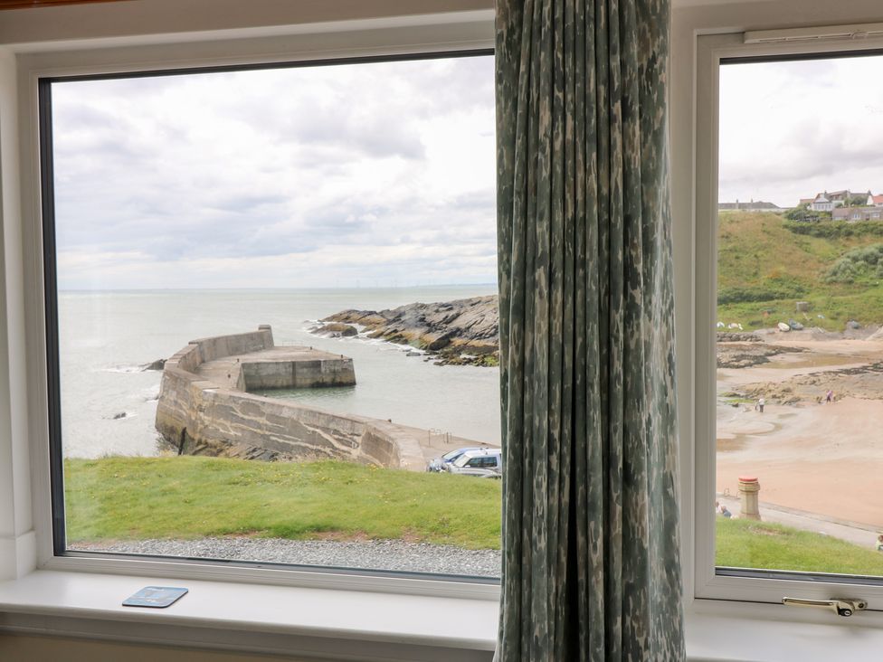 A view of a beach and pier from a window at The Breakers in Newburgh, Aberdeenshire