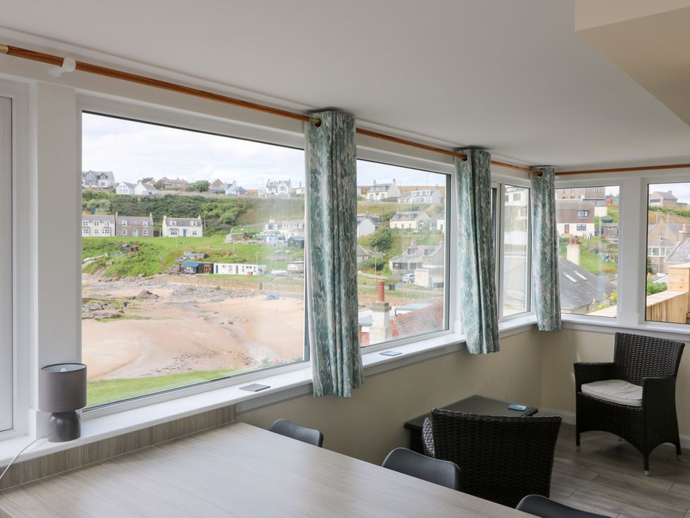 A dining room with windows and furniture at The Breakers in Newburgh, Aberdeenshire