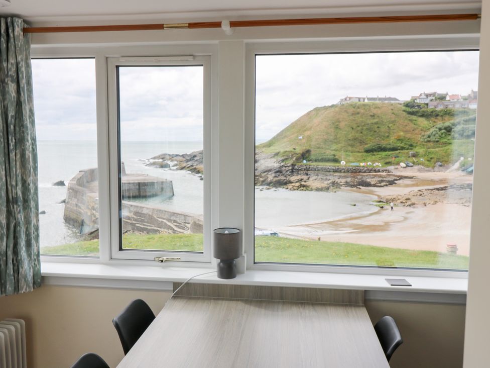 A dining room with windows overlooking the sea at The Breakers in Newburgh, Aberdeenshire