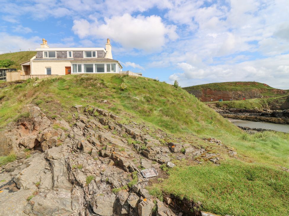 A house on a hill surrounded by grass and rocks at The Breakers in Newburgh, Aberdeenshire