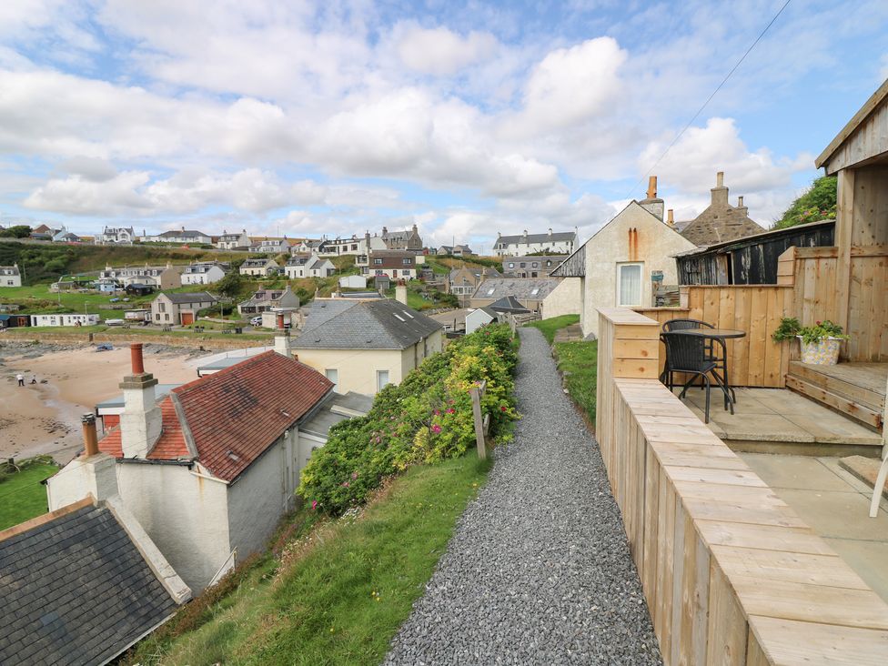 A pathway leading through houses with a beach in the background at The Breakers in Newburgh, Aberdeenshire