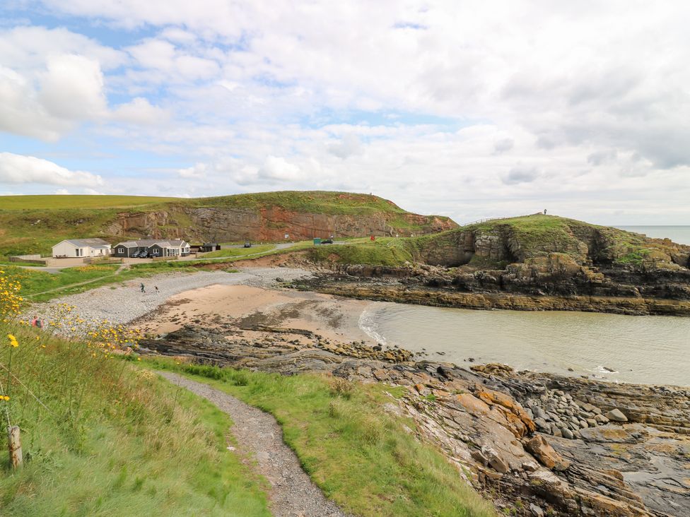 A beach with a rocky shoreline and houses at The Breakers in Newburgh, Aberdeenshire