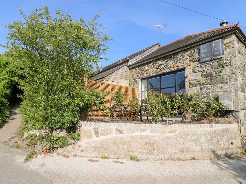 A barn with outdoor seating and plants at Joe's Barn in Mullion