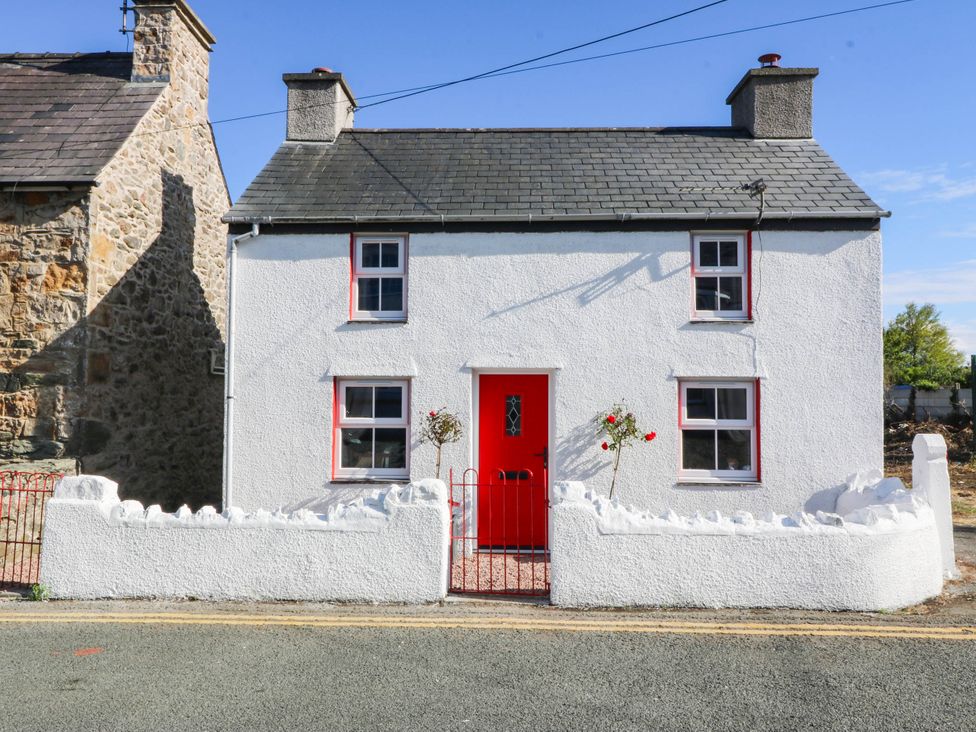 A house with a red door and white walls at Pant in Llanfairpwllgwyngyll