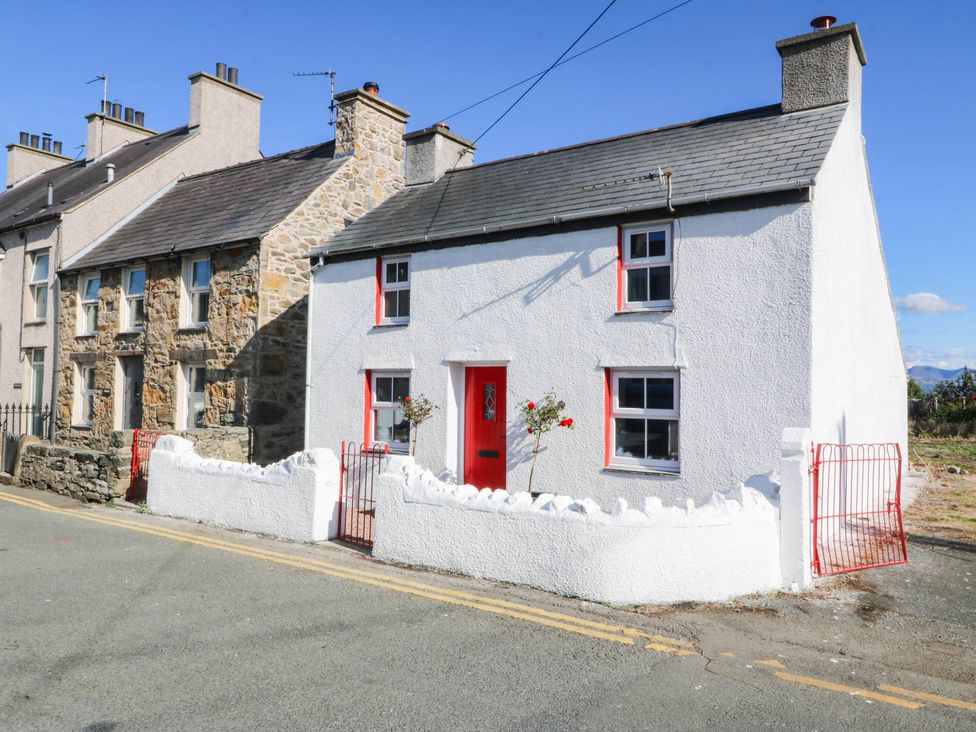 A house with a stone wall and a red front door at Pant in Llanfairpwllgwyngyll