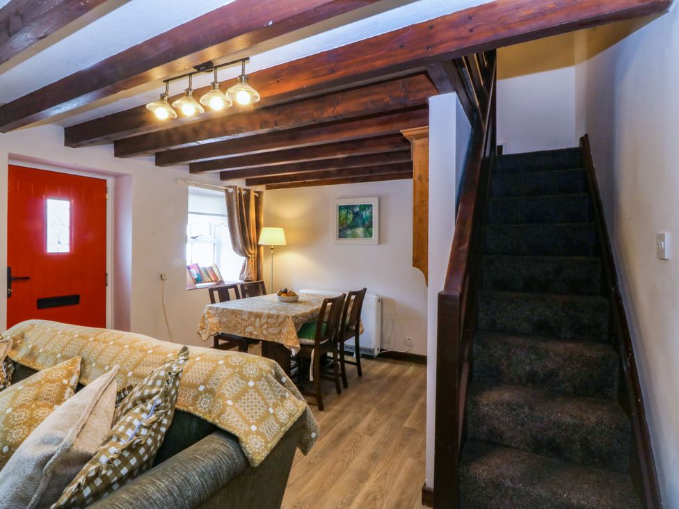 A living room with a dining table and stairs at Pant in Niwbwrch (newborough)