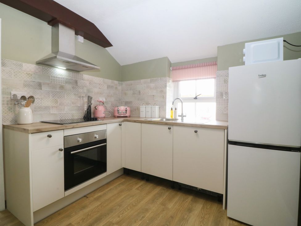 A kitchen with an oven, sink, refrigerator, and utensils at Pant in Niwbwrch (newborough)