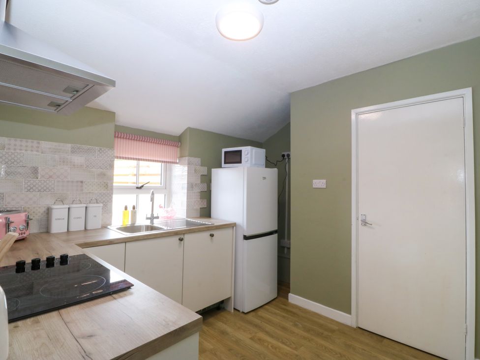 A kitchen with a refrigerator and stove at Pant in Niwbwrch (newborough)