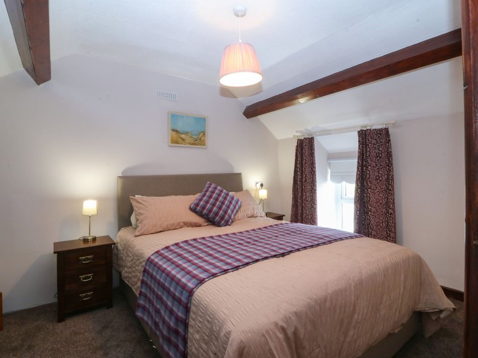 A bedroom with a bed and nightstand at Pant in Niwbwrch (newborough)