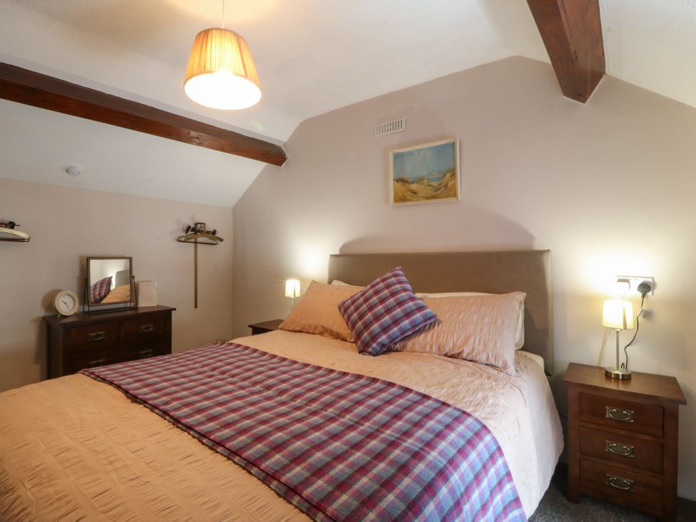 A bedroom with a bed and bedside tables at Pant in Niwbwrch (newborough)