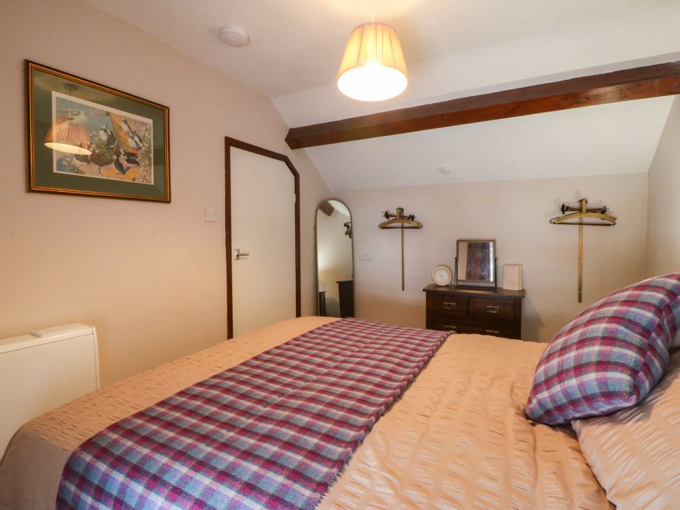 A bedroom with a bed and dresser at Pant in Niwbwrch (newborough)