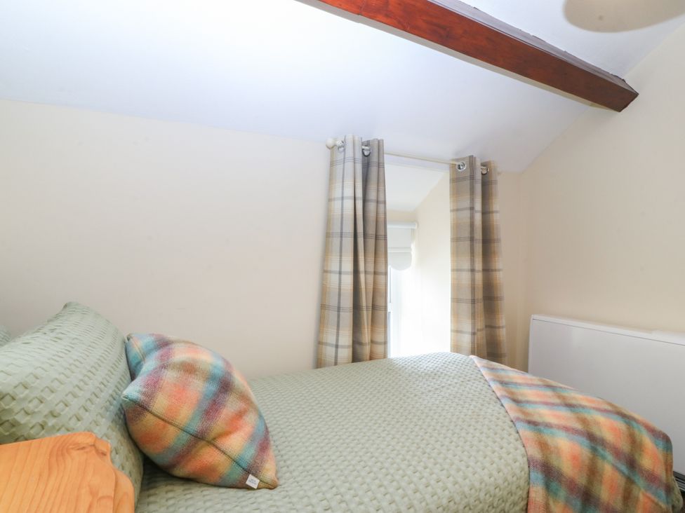 A bedroom with a bed and curtains at Pant in Niwbwrch (newborough)