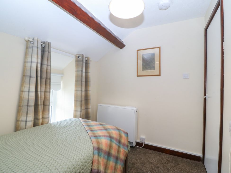 A bedroom with a bed and curtains at Pant in Niwbwrch (newborough)