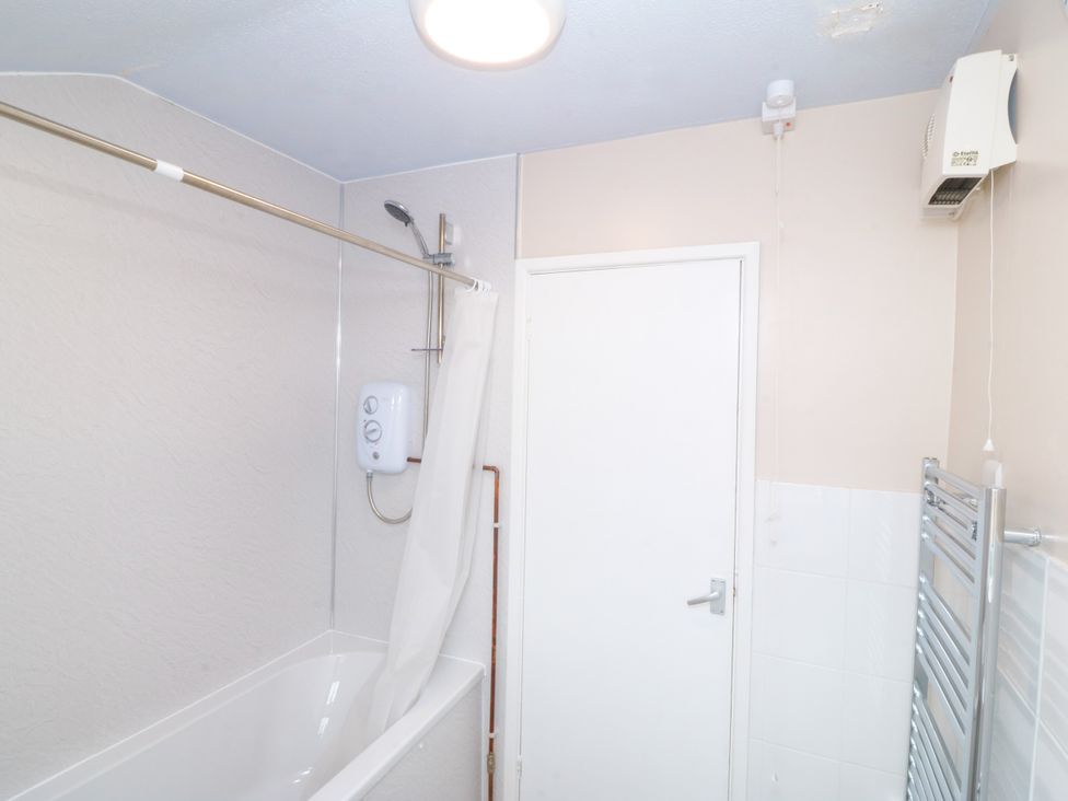 A bathroom with a bath tub and shower at Pant in Niwbwrch (newborough)