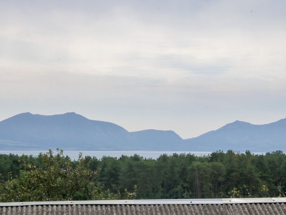 A view of mountains and a lake with trees in the foreground at Tir Mawr in Llanfairpwllgwyngyll