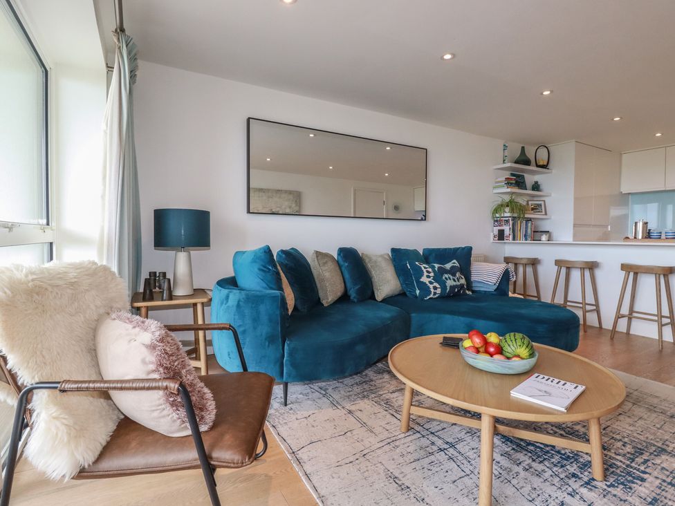 A living room with a sofa, table, and bookshelf at 4 Ocean Gate in Newquay