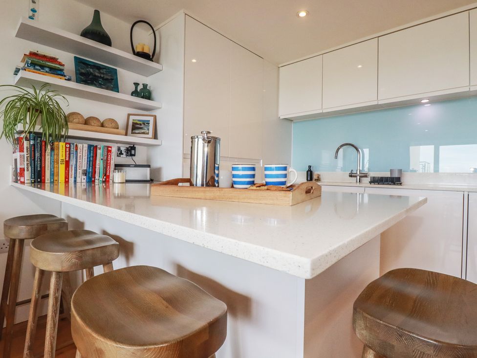 A kitchen with a central island and bar stools at 4 Ocean Gate in Newquay