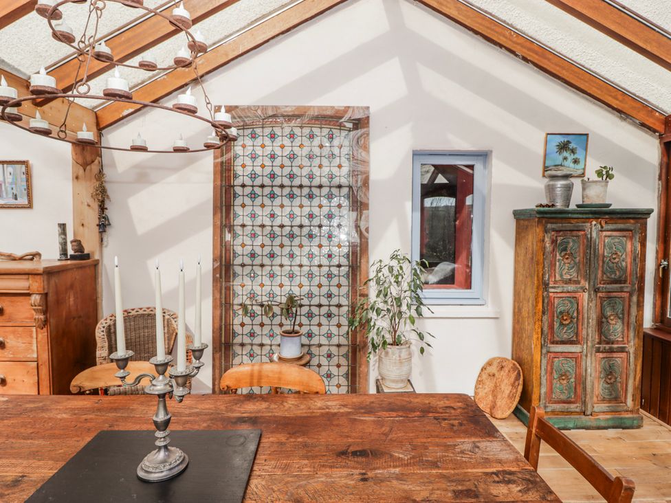 A dining room with a wooden table candle holder and decorative cabinet at Pencestyll, Cardigan