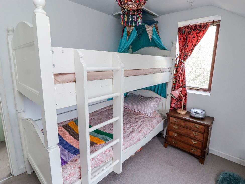 A bunk bed with a nightstand and lamp in a bedroom at Pencestyll in Cardigan
