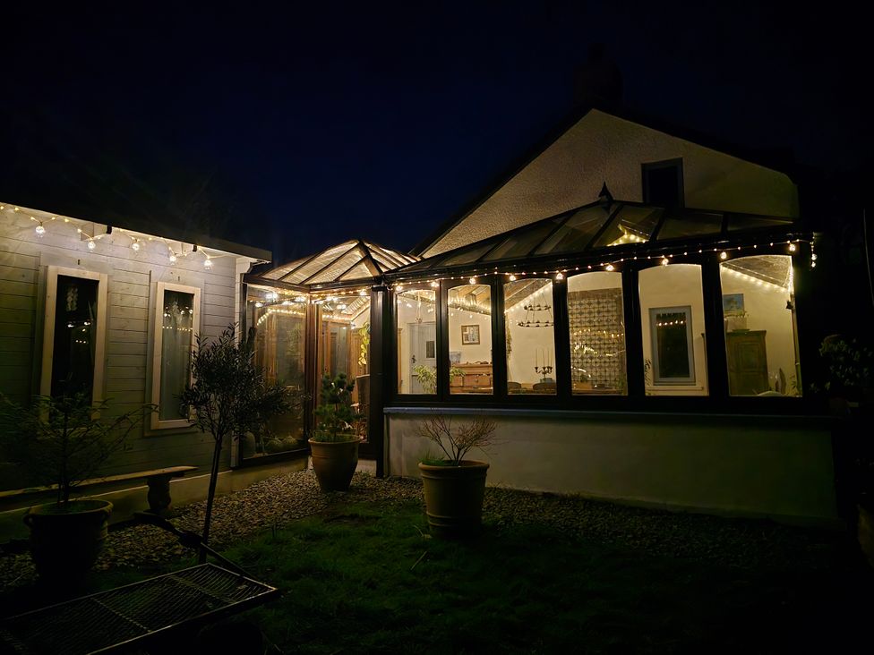 A conservatory with string lights and potted plants at Pencestyll in Bridell near Cilgerran