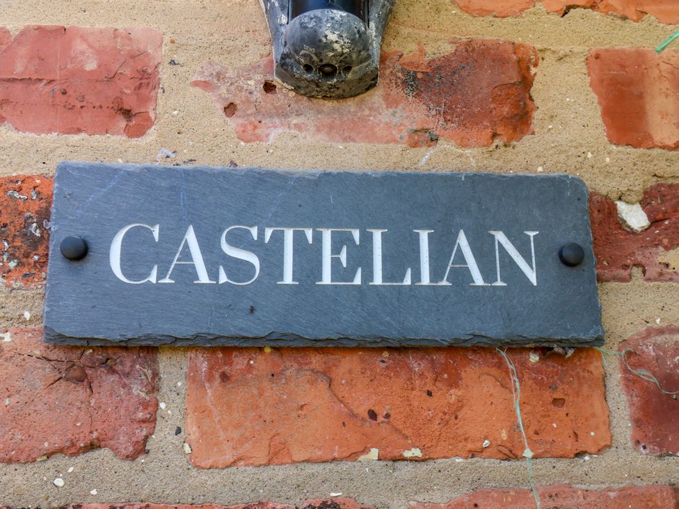 A slate sign with the name Castelian on a brick wall at Castelian in Flamborough