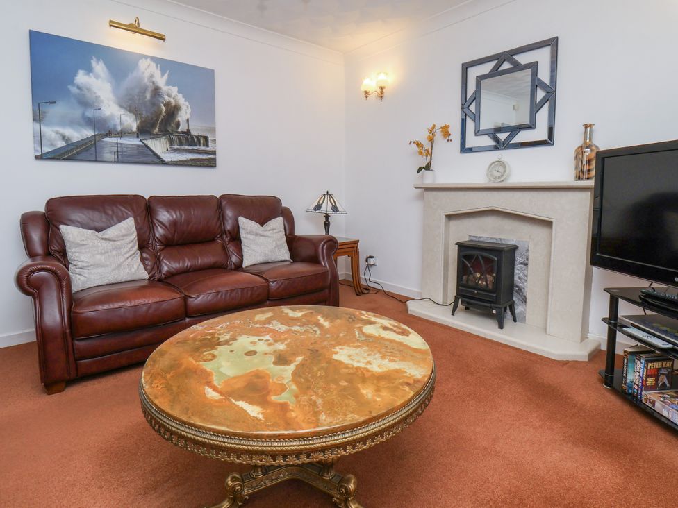 A living room with a sofa, coffee table, and fireplace at Castelian in Flamborough