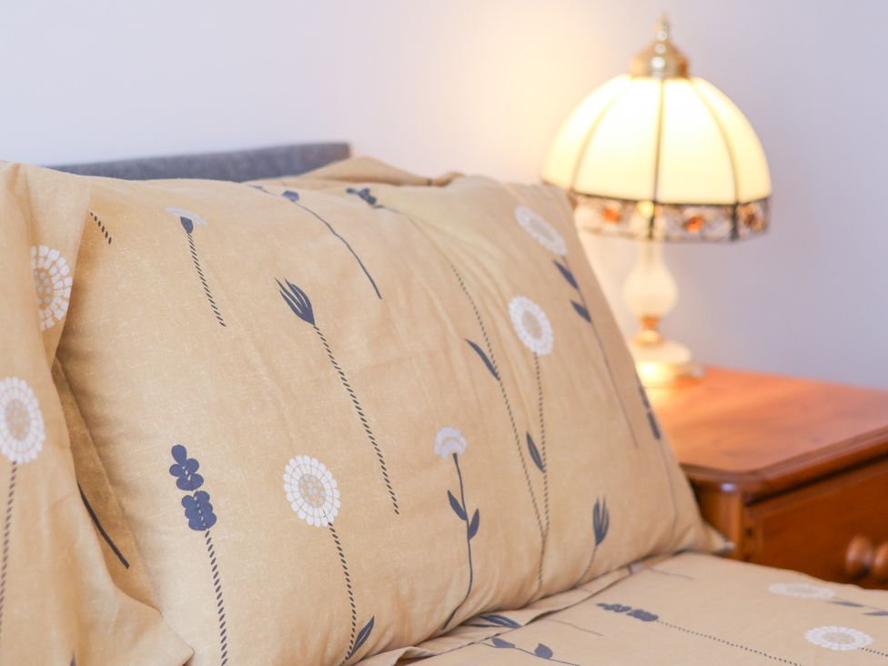 A bed with patterned bedding and a lamp on a nightstand at Castelian in Flamborough