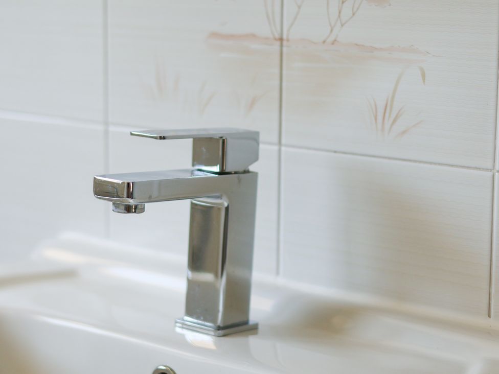 A faucet on a sink with tiled background at Castelian in Flamborough