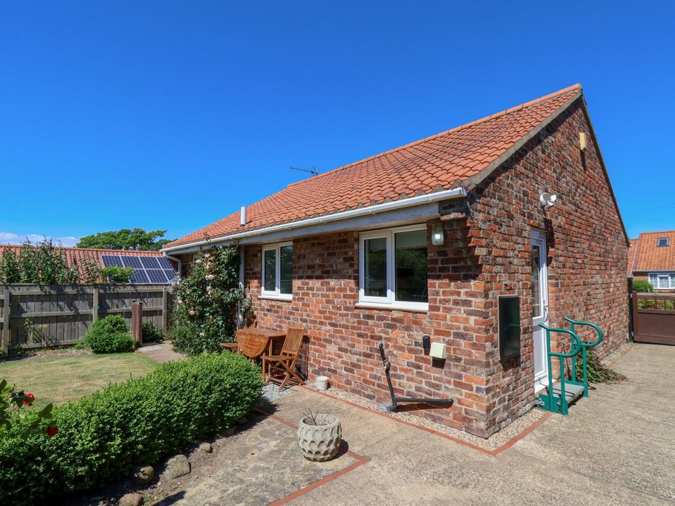 A garden with outdoor furniture and a brick building at Castelian in Flamborough