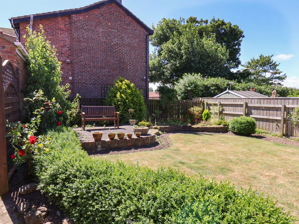 A garden with a bench and potted plants at Castelian in Flamborough