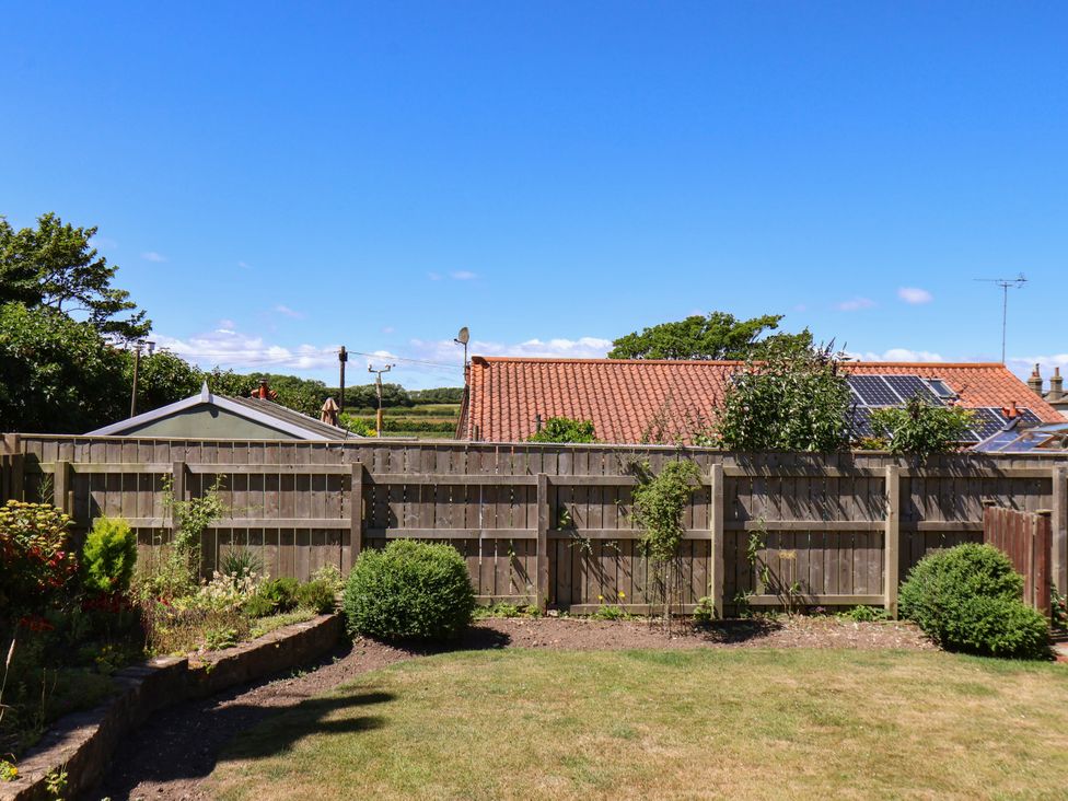A garden with a fence and plants at Castelian in Flamborough