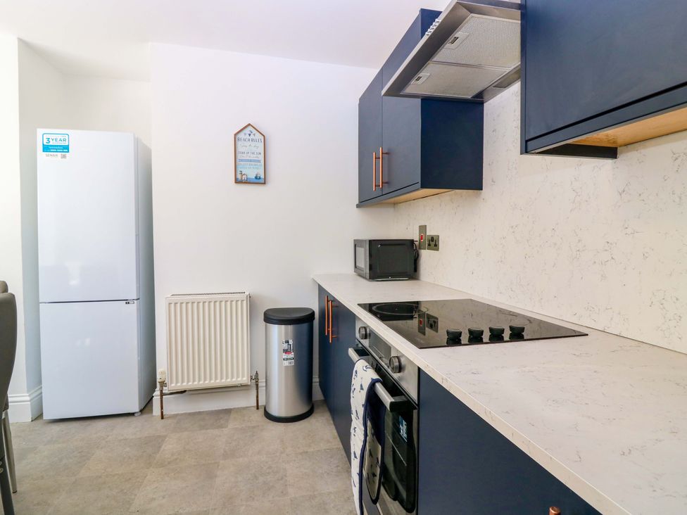 A kitchen with a refrigerator, microwave, stove, and trash can at No.9 North St in Fraserborough