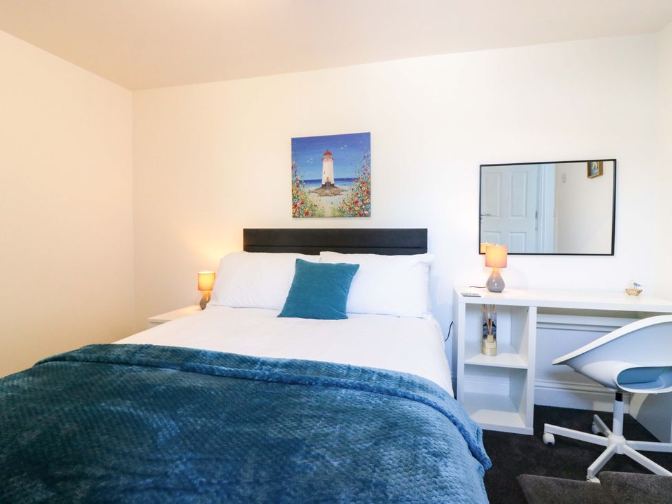A bedroom with a bed, desk, and painting at No.9 North St Fraserborough