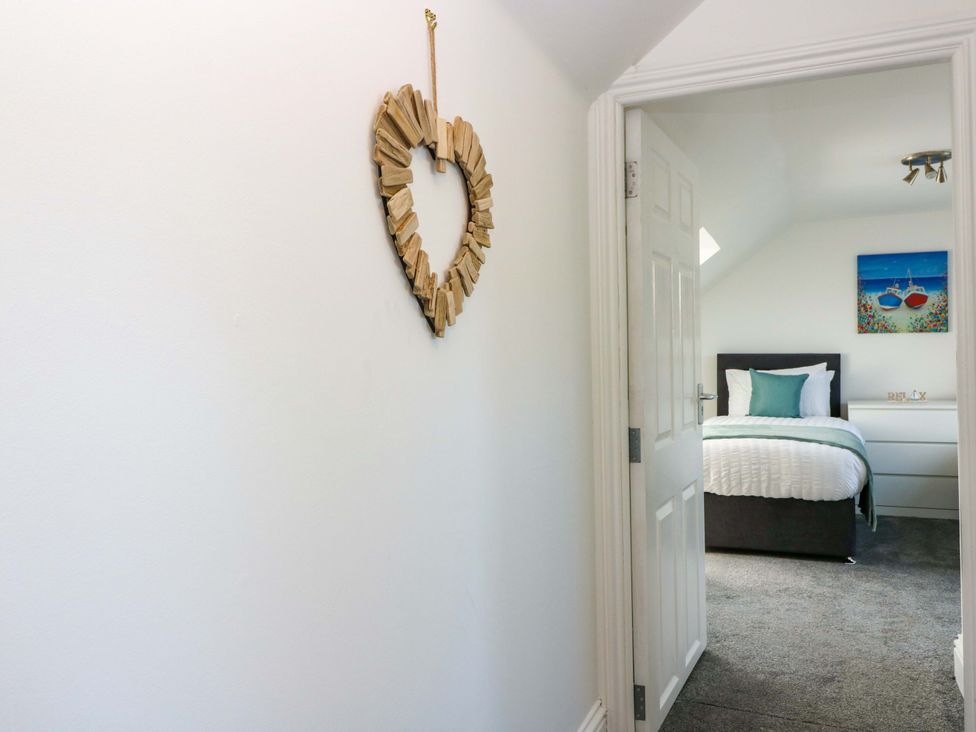 A hallway leading to a bedroom with a bed and painting at No.9 North St, Fraserborough