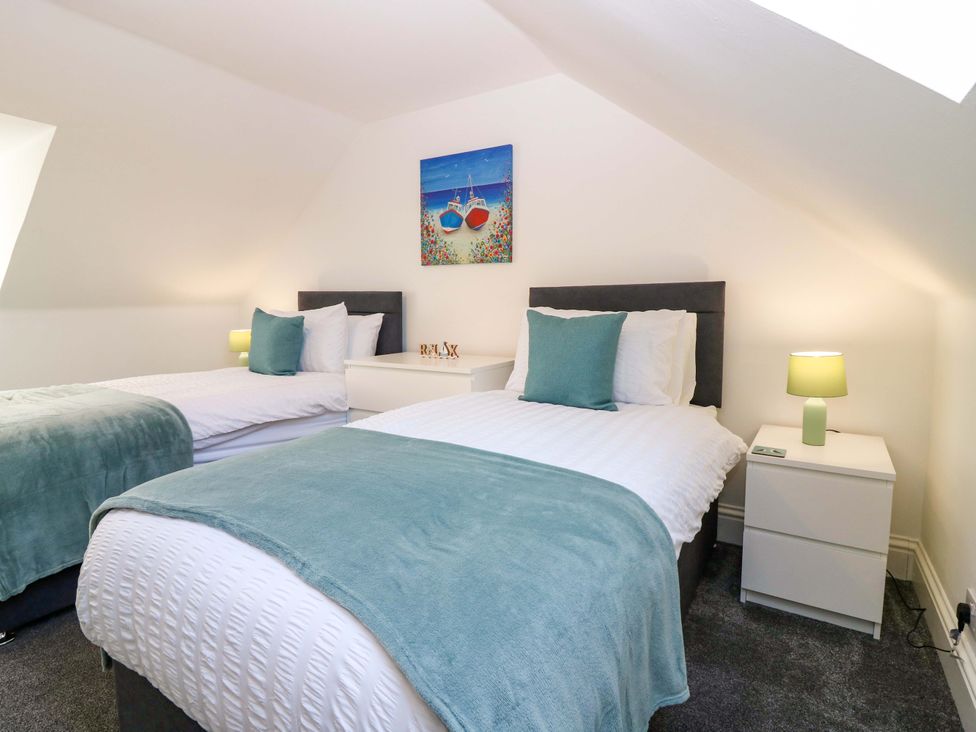 A bedroom with two beds and a painting at No.9 North St in Fraserborough