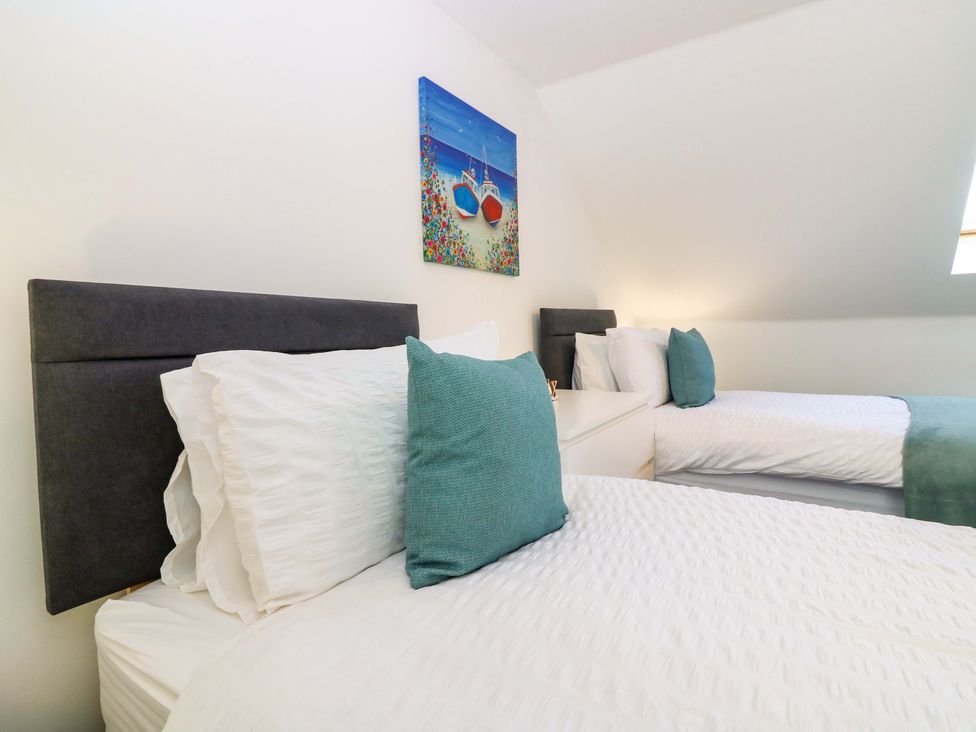 A bedroom with two beds and a painting at No.9 North St Fraserborough
