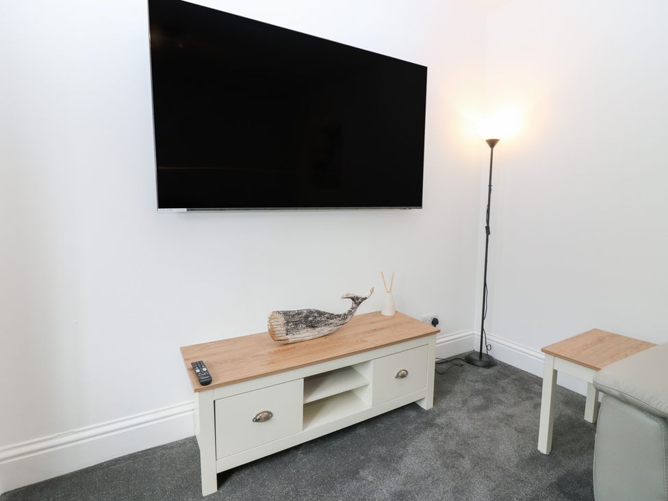 A living room with a television mounted on the wall and a TV stand at No.9 North St, Fraserburgh