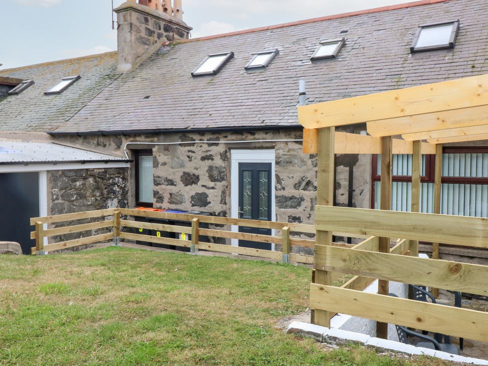 An outdoor area with a stone wall house and wooden fence at No.9 North St in Fraserburgh