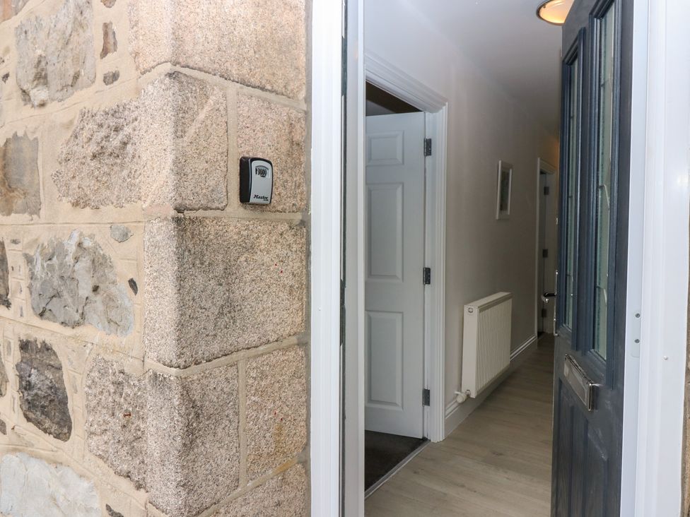 A hallway with a front door and stone wall at No.9 North St Fraserburgh