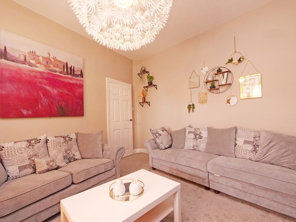 A living room with a sofa, table, and wall decorations at Ashville Grange in Scarborough