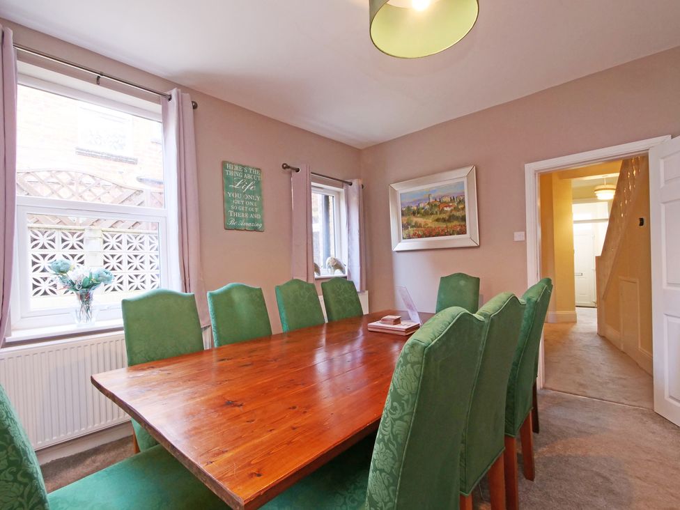 A dining room with a wooden table and green chairs at Ashville Grange in Scarborough