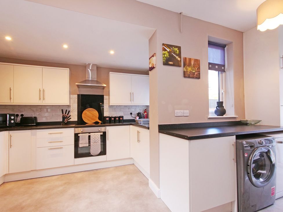 A kitchen with cabinets, stove, and washing machine at Ashville Grange in Scarborough